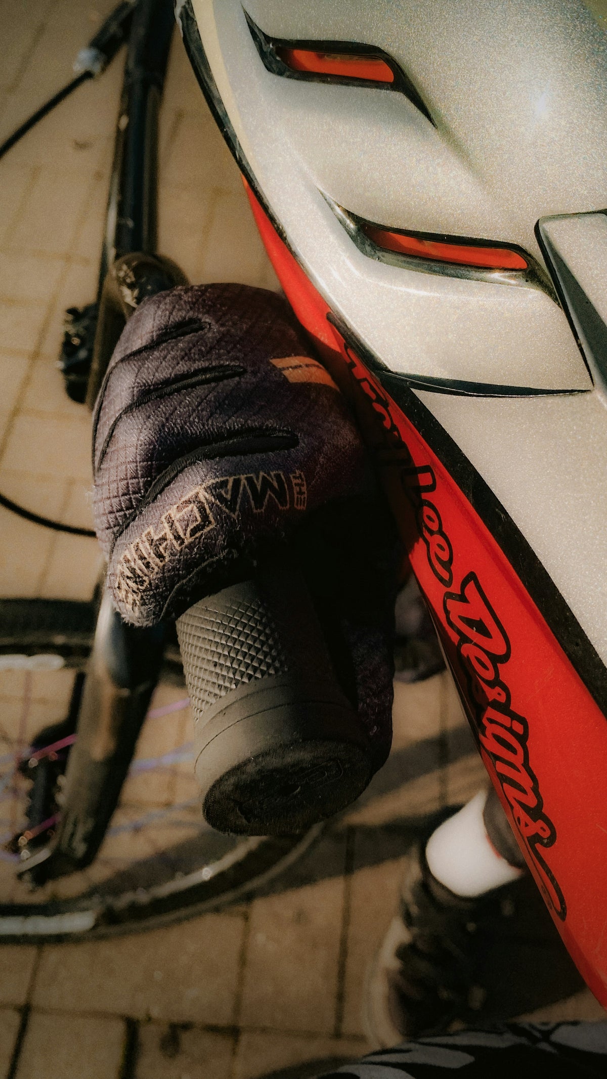 Main gantée posée sur le guidon d'un vélo, casque à côté