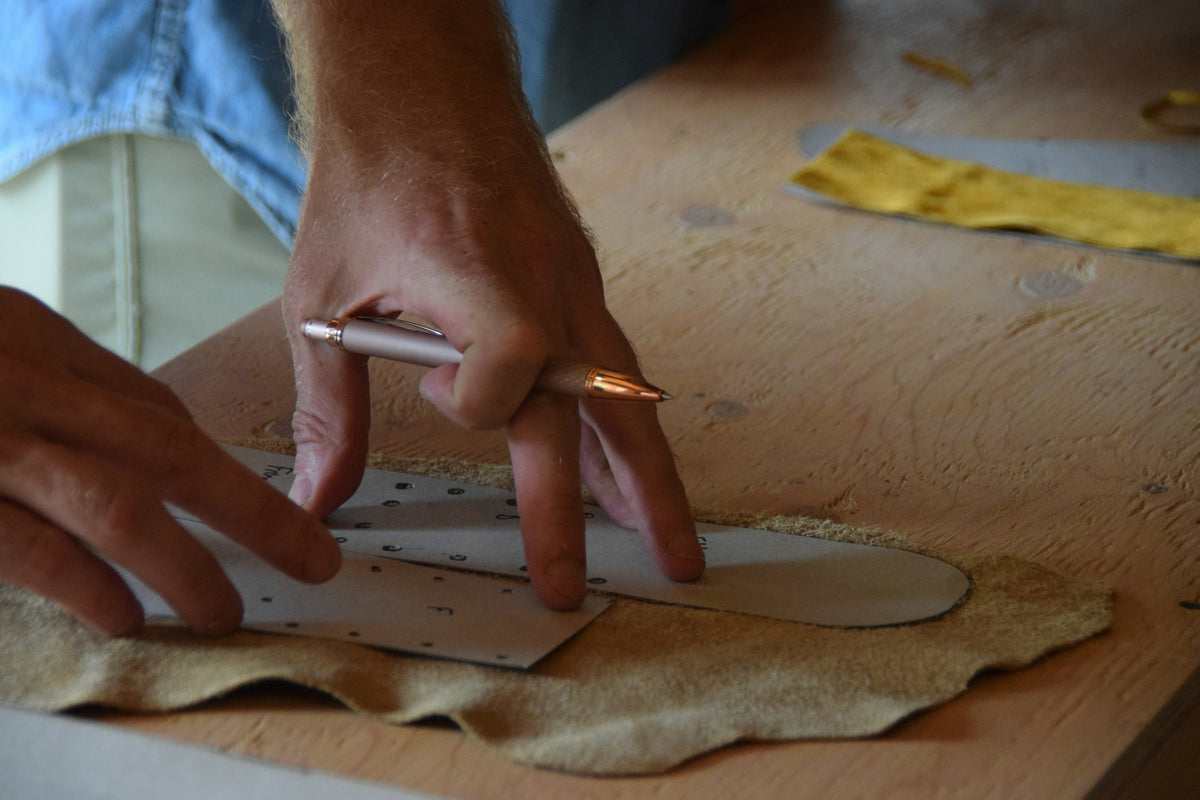 Artisan traçant un patron au stylo sur du cuir