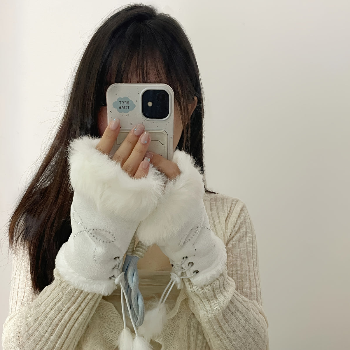 Mitaines femme blanches portées, doigts libres tenant un téléphone