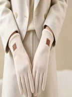 Gants femme polaire beige portés avec un manteau clair, badge au poignet