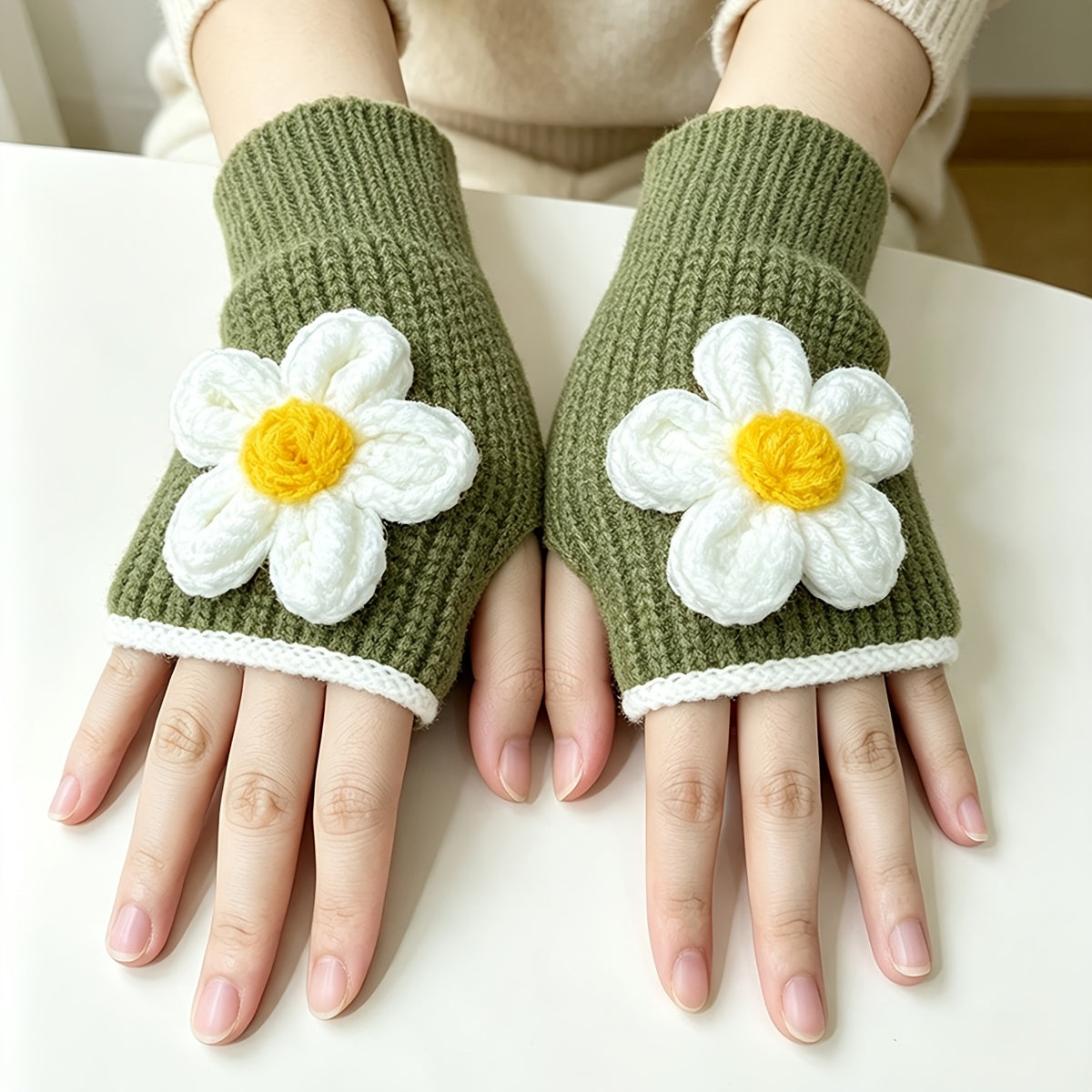 Mitaines vertes à marguerite posées sur une table blanche