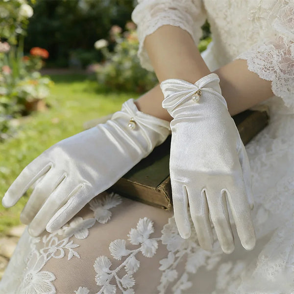 Gants de cérémonie femme en satin blanc, gros plan sur le poignet froncé et la perle