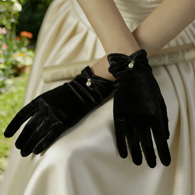 Gants femme en satin noir portés, mains croisées sur une robe claire