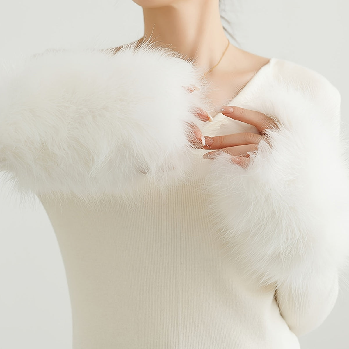Mitaines blanches en fausse fourrure portées sur un pull écru
